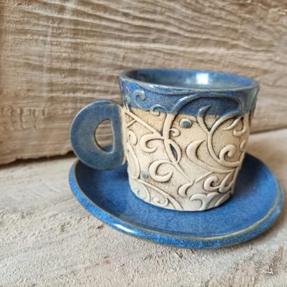 Photo of ceramic coffee cup with handle and saucer in blue colour
