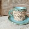 Photo of ceramic coffee cup with handle and saucer in light blue colour
