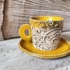 Photo of ceramic coffee cup with handle and saucer in yellow colour