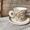 Photo of ceramic coffee cup with handle and saucer in beige colour