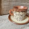 Photo of ceramic coffee cup with handle and saucer in brown colour